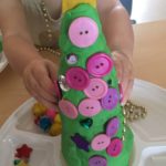 Child engaging with playdough, decorating playdough Christmas tree at daycare